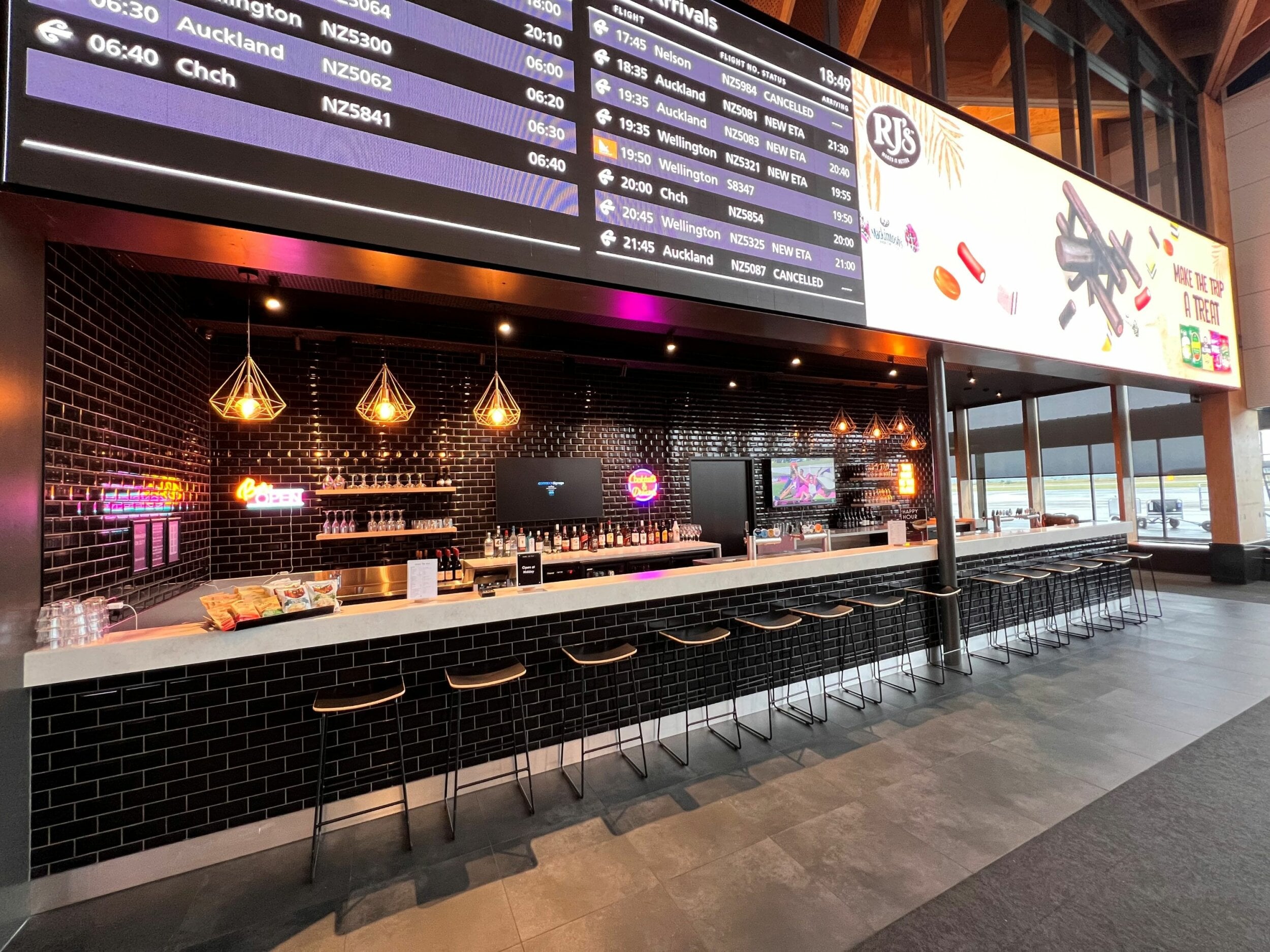 The Fuel to Fly bar, showing bar stools in front of the bar counter, drinks and lighting behind.