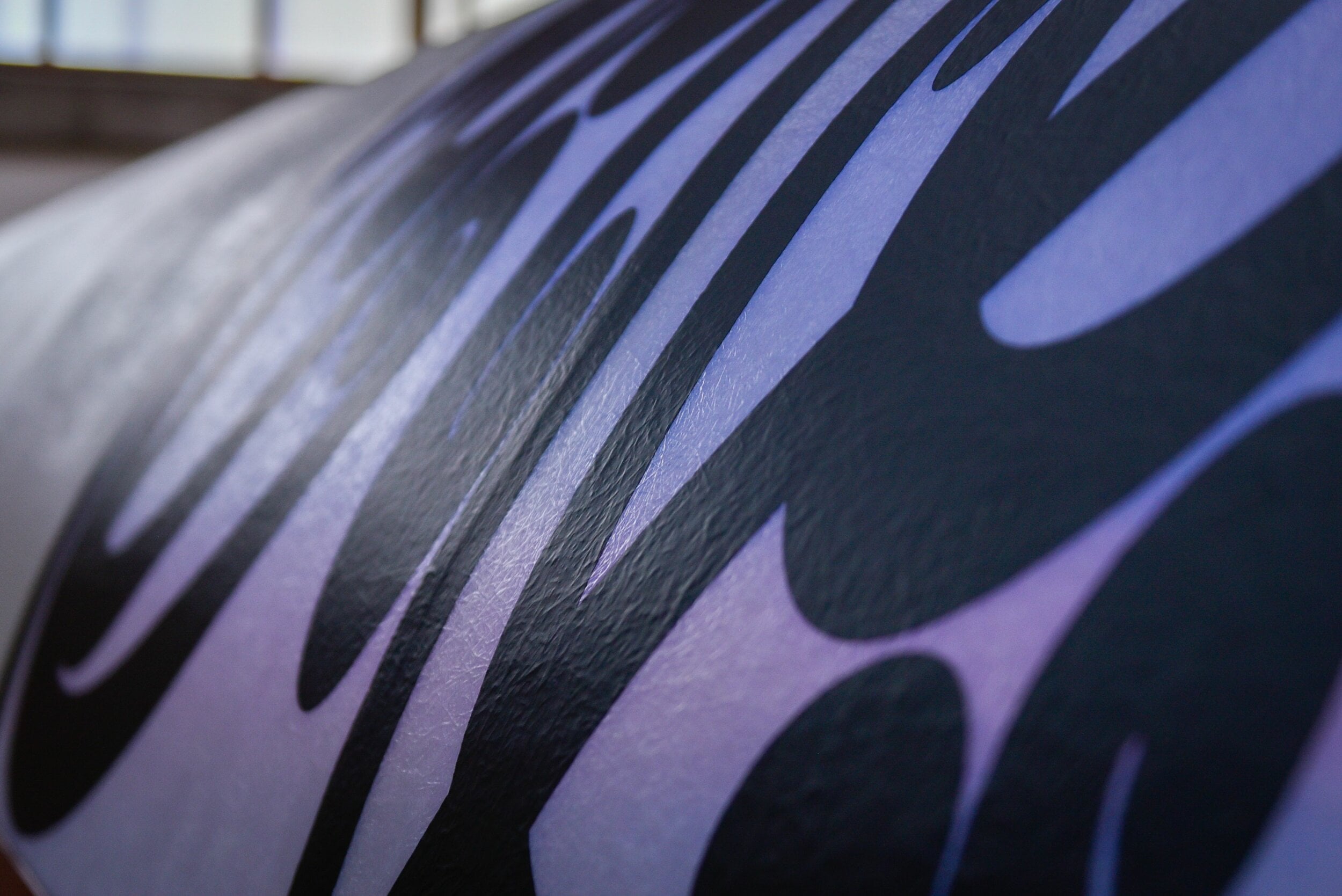 A close up of the patterning on a section of the waka Aorere Ararau, illuminated purple.